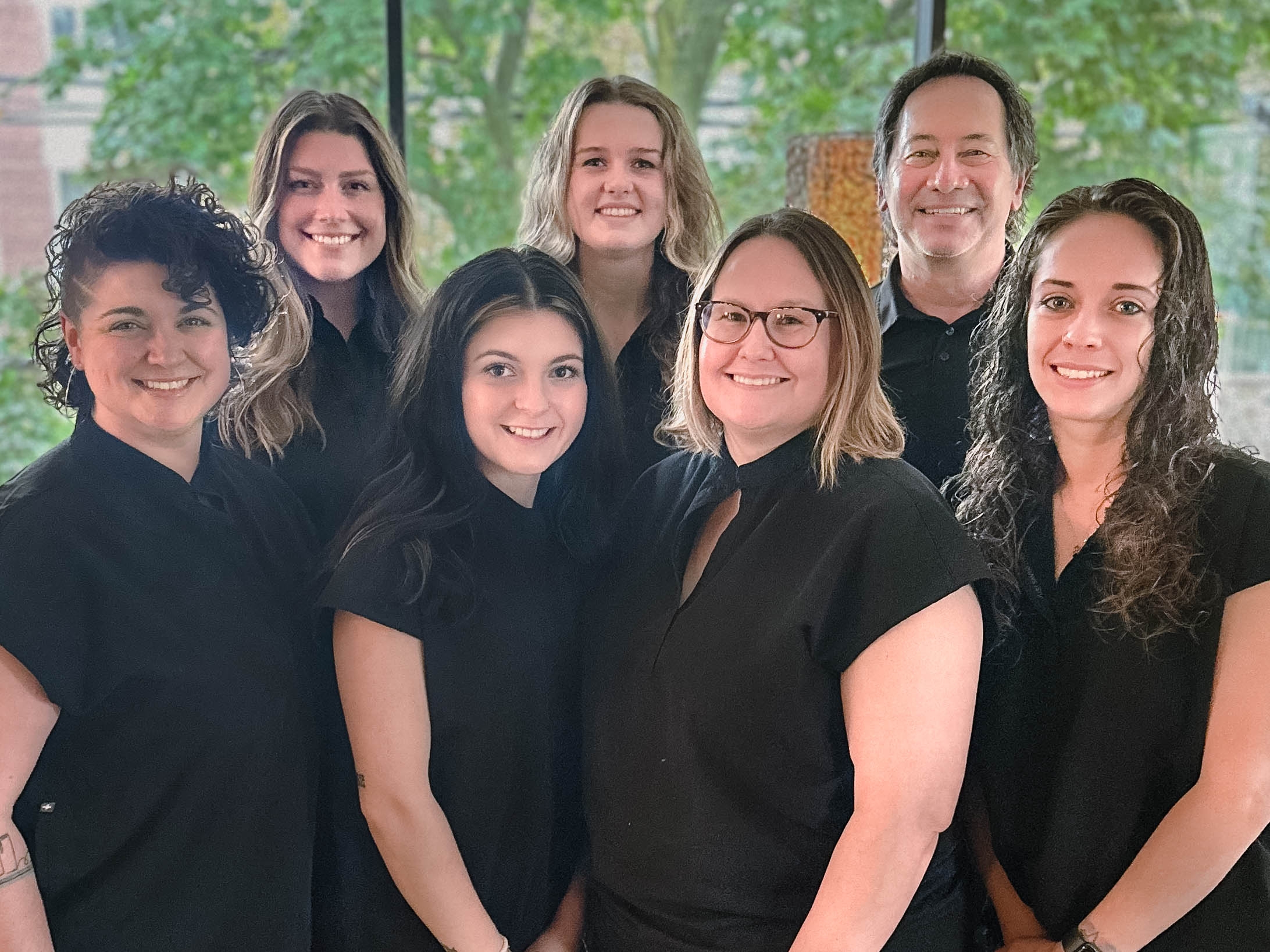 Photo of the DeWan Team in the office, all wearing green scrubs other than Mike DeWan